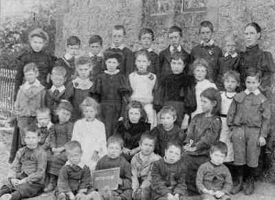 The pupils and teachers of Nutbourne Church of England School at the turn of the twentieth century. In total twenty-eight children are pictured (17 boys and 11 girls) as well as two teachers at each end of the back row